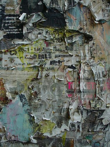 Layers of torn street posters on a weathered wall